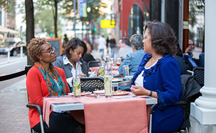 Three women having lunch on a sunny day at the outside tables on Penn Avenue