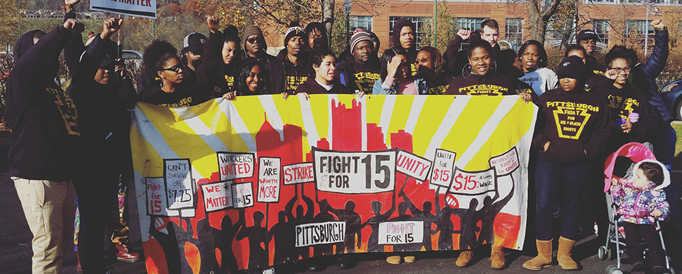 Large group of workers posed holding a "Fight for 15" banner