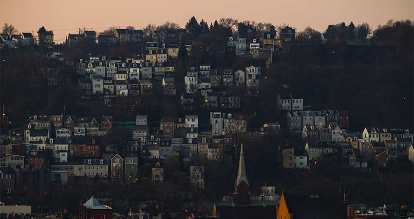 houses on a hillside with a pink sky above