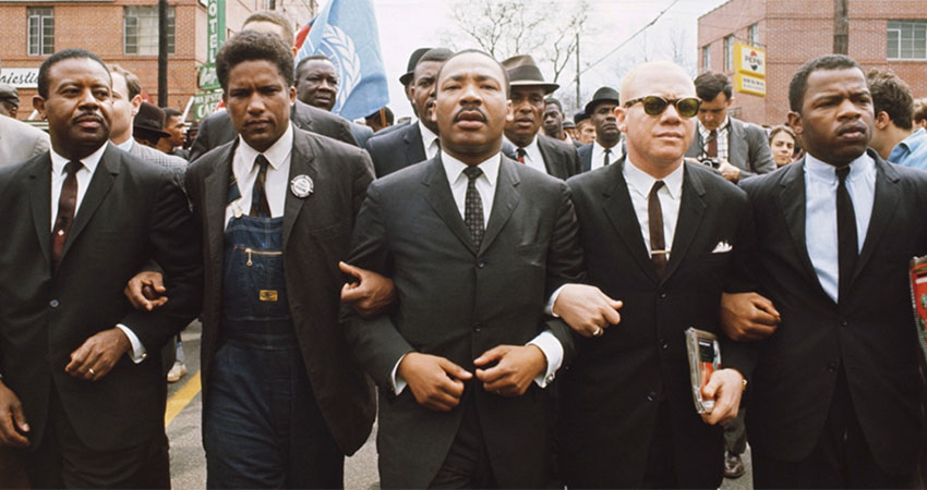 Martin Luther King and other men marching with arms locked.