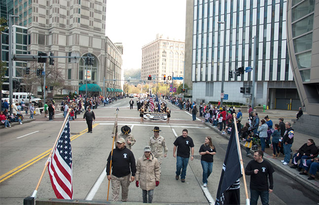 Photo of veterans marching Downtown on Liberty Avenue in the Veterans Day parade with spectators lining the street.