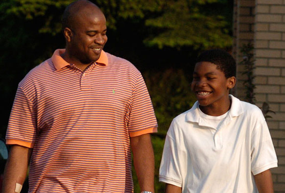 African American man and youth walking down the street together.