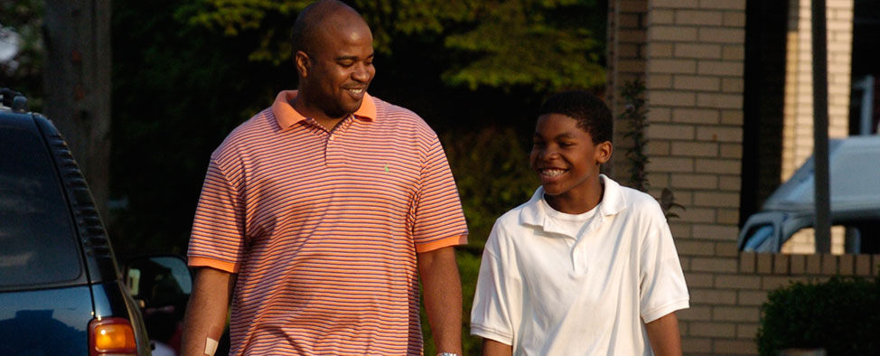 African American man and youth walking down the street together.