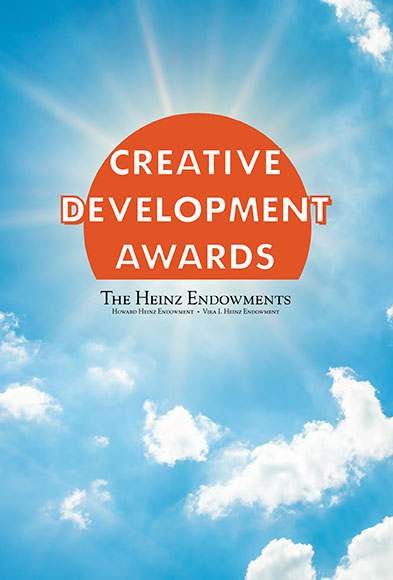 White clouds, blue sky, and in place of the sun - orange circle containing the words, "Creative Development Awards"