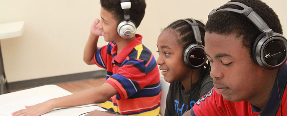 Four young men with headphones in recording studio.