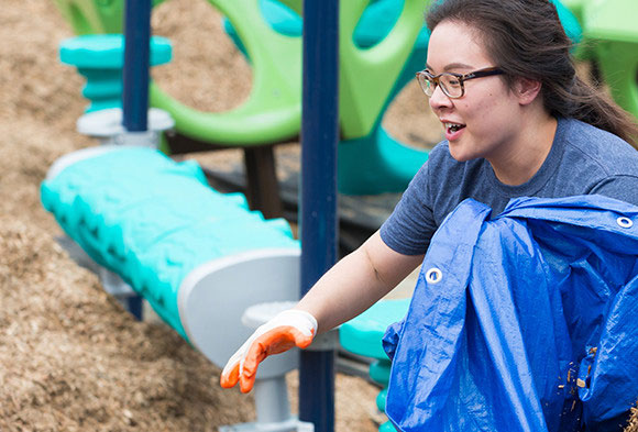 Two volunteers carrying mulch in a blue tarp on Build Day at the Hazelwood KaBOOM! playground.