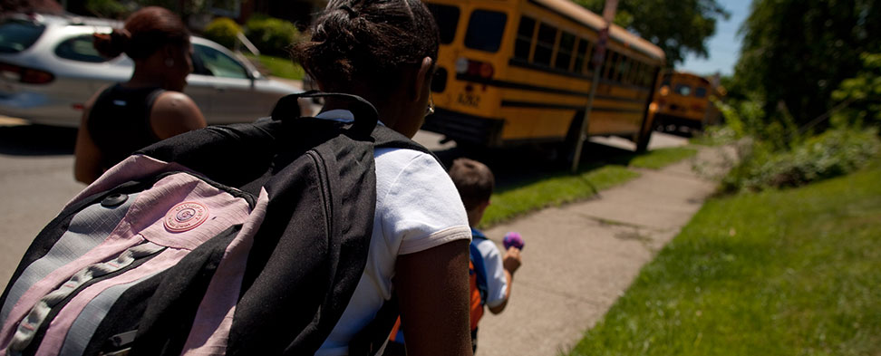 Photo taken from behind of children boarding their school bus to attend the Environmental Charter School.