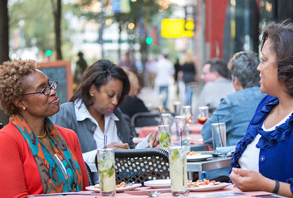 Three woman having lunch on a sunny day at the outside tables on Penn Avenue.