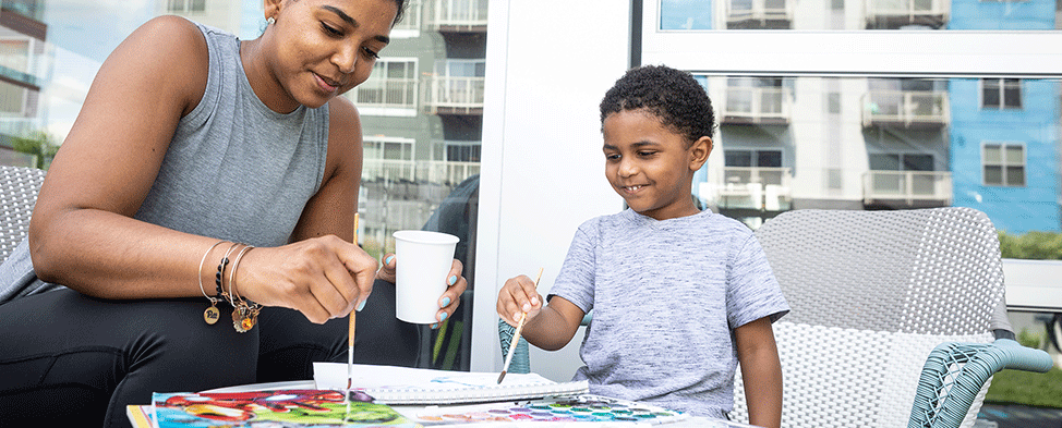 A Pre-K mom and her son sitting at a table painting together.