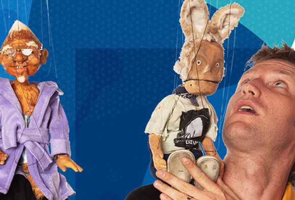 Two men are looking up at the string puppets from "The Dragon of Polish Hill" that are sitting on their shoulders.