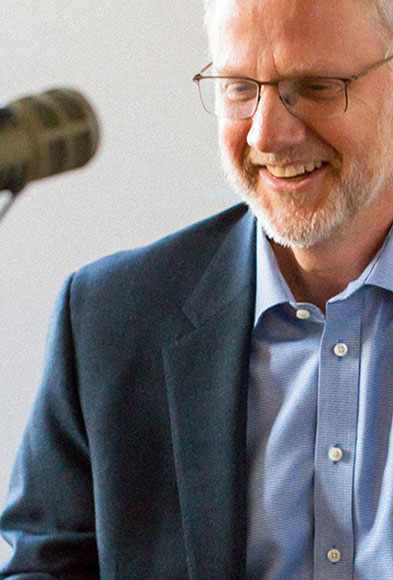 Grant Oliphant smiling in conversation with podcast guest seated behind a microphone.