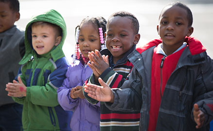 Four happy young children clapping their hands and smiling when the Storymobile visited Propel Elementary school in Hazelwood.