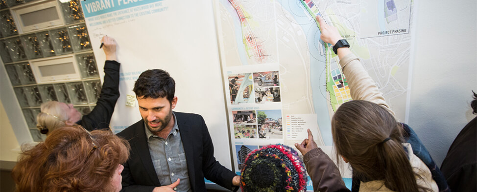 Hazelwood community members talking to developers about the Hazelwood Green development. They are pointing to different sections of the master plan and writing comments.