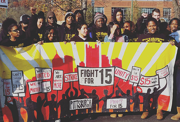 Large group of workers posed holding a "Fight for 15" banner