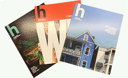 Covers of three issues of h magazine, fanned-out.
