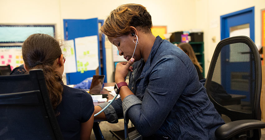 Woman with a stethoscope is tending to a young girl in an asthma clinic.