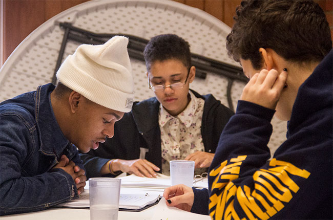 Three young men working around the table who are participating in the Dreams of Hope program.