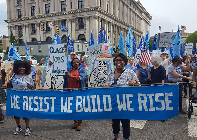 New Voices Pittsburgh at the Climate March in Pittsburgh, marching behind a banner and holding signs about climate, justice, job, clean air and more.